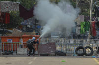 An anti-coup protester uses a fire extinguisher behind a line of women's clothing hanged across a road to deter security personnel from entering the protest area in Yangon, Myanmar Tuesday, March 9, 2021. In Burmese culture, walking underneath women's clothing is believed to weaken the power of men and bring bad fortune. (AP Photo)