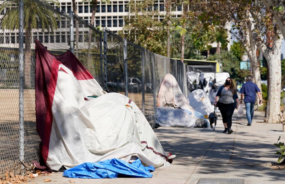 Pedestrians walk past a homeless encampment just outside Grand Park on Wednesday in Los Angeles.