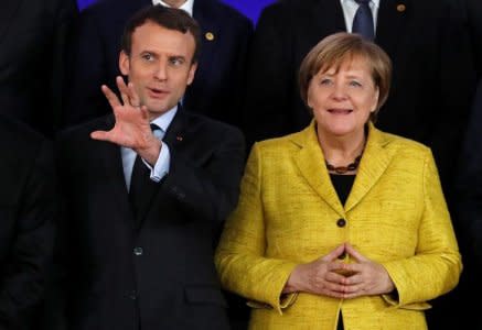FILE PHOTO: French President Emmanuel Macron and German Chancellor Angela Merkel take part in a group photo on the launching of the Permanent Structured Cooperation, or PESCO, a pact between 25 EU governments to fund, develop and deploy armed forces together, during a EU summit in Brussels, Belgium, December 14, 2017. REUTERS/Yves Herman
