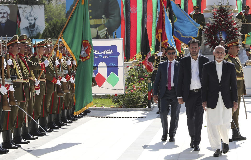 In this photo released by the Afghan Presidential Palace, Afghan President Ashraf Ghani, right, inspects the guard of honor during Independence Day celebrations at Defense Ministry in Kabul, Afghanistan, Monday, Aug. 19, 2019. Afghanistan's president is vowing to eliminate all safe havens of the Islamic State group as the country marks a subdued 100th Independence Day after a horrific wedding attack claimed by the local IS affiliate. (Afghan Presidential Palace via AP)