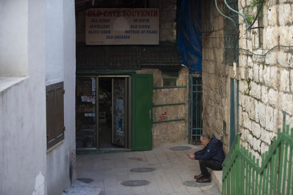 A Palestinian vendor stands in front of his shop near the Church of the Nativity, traditionally believed to be the birthplace of Jesus Christ, in the West Bank City of Bethlehem, Monday, Nov. 23, 2020. Normally packed with tourists from around the world at this time of year, Bethlehem resembles a ghost town – with hotels, restaurants and souvenir shops shuttered by the pandemic. (AP Photo/Majdi Mohammed)