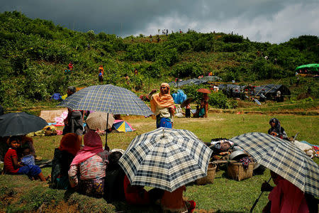 New Rohingya refugees sit on the ground as others clean bushes off of a hill to build makeshift shelters in Balukhali near Cox’s Bazar, Bangladesh, September 2, 2017. REUTERS/Mohammad Ponir Hossain