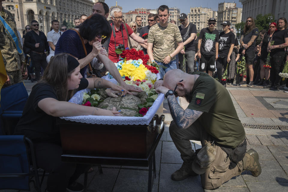 A serviceman pays his last respects at the coffin of volunteer soldier Ivan Shulga, a sound producer in TV channels and musician, killed in a battle with the Russian troops near Bakhmut, during a farewell ceremony in Independence Square in Kyiv, Ukraine, Tuesday, June 20, 2023. (AP Photo/Efrem Lukatsky)