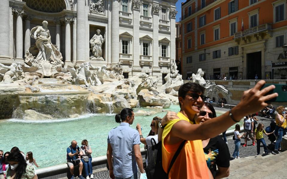 A couple takes a selfie photo as people gather by the Trevi fountain - AFP