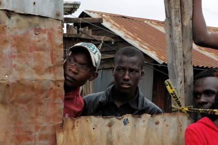 People watch as rescue teams and police officers search the debris of a collapsed school classroom, in Nairobi