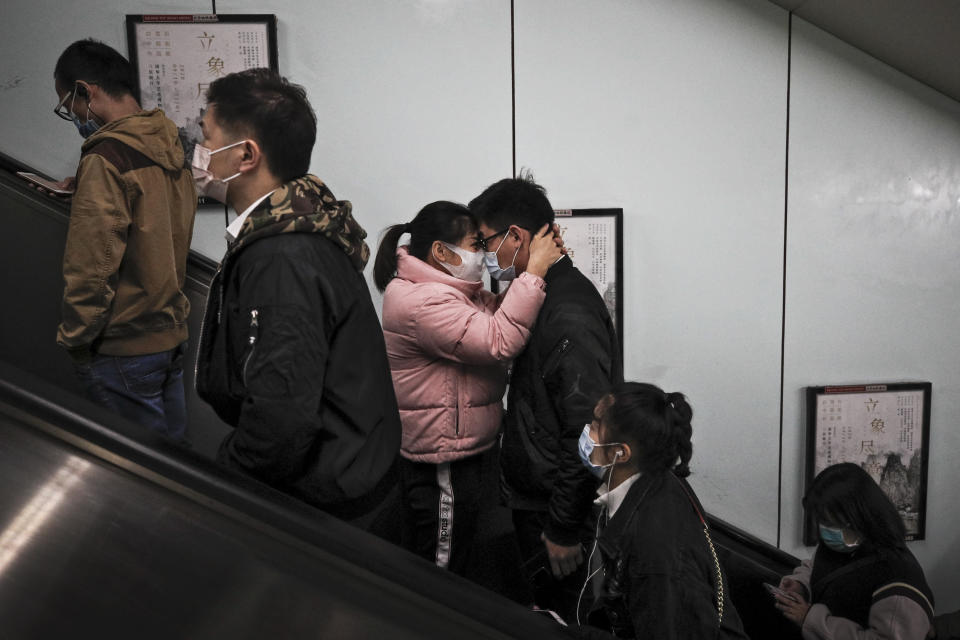 A couple wearing face masks to help curb the spread of the coronavirus hug each other as they exit a subway station with commuters during the morning rush hour in Beijing, Thursday, Oct. 29, 2020. (AP Photo/Andy Wong)