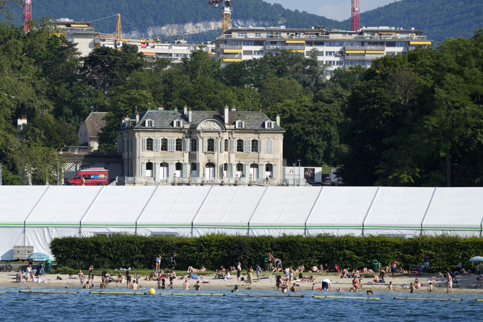 People swim on the shores of Lake Geneva in front of a tent that was set up as a media center opposite the 'Villa La Grange' the venue for the upcoming meeting between US President Joe Biden and Russian President Vladimir Putin, in Geneva, Switzerland Monday, June 14, 2021. The lakeside city known as a Cold War crossroads and a hub for Swiss discretion, neutrality and humanitarianism, is set to return to a spotlight on the world stage as U.S. President Joe Biden and Russian President Vladimir Putin come to town for a summit on Wednesday, June 16.(AP Photo/Markus Schreiber)