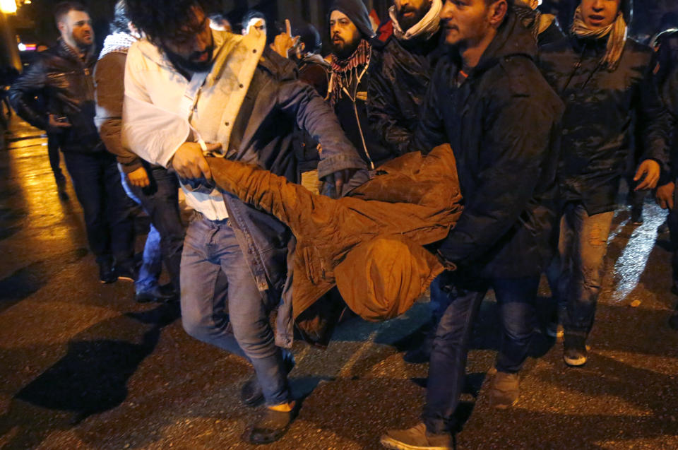 Anti-government protesters carry their friend who was injured by rubber bullet while clashing with the riot police, during ongoing protests against the political elites who have ruled the country since decades, in Beirut, Lebanon, Sunday, Jan. 19, 2020. Lebanese security forces used tear gas, water cannons and rubber bullets in clashes with hundreds of anti-government protesters outside the country's Parliament on Sunday, as violence continued to escalate in a week of rioting in the capital. (AP Photo/Hussein Malla)