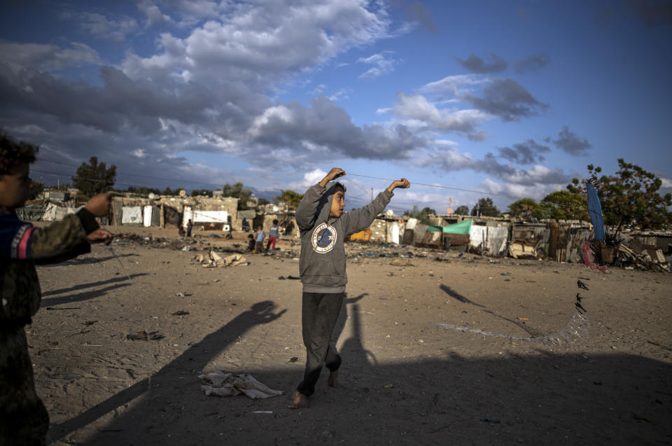 Palestinian children fly kites in a slum on the outskirts of Khan Younis Refugee Camp, in the southern Gaza Strip, Wednesday, Nov. 25, 2020. Israel's blockade of the Hamas-ruled Gaza Strip has cost the seaside territory as much as $16.7 billion in economic losses and caused its poverty and unemployment rates to skyrocket, a U.N. report said Wednesday, as it called on Israel to lift the 13-year closure. (AP Photo/Khalil Hamra)