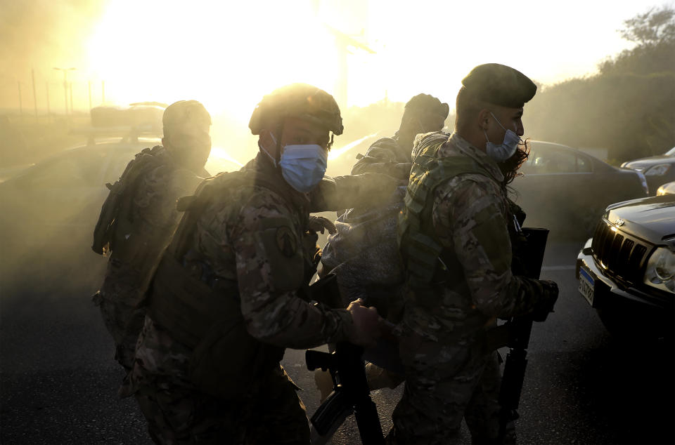 Lebanese soldiers arrest a protester who was burning tires to block a highway that leads to Beirut's international airport, in Beirut, Lebanon, Tuesday, March 2, 2021. Scattered protests broke out in different parts of Lebanon Tuesday after the Lebanese pound hit a record low against the dollar on the black market, a sign of the country's multiple crises deepening with no prospects for a new Cabinet in the near future. (AP Photo/Hussein Malla)