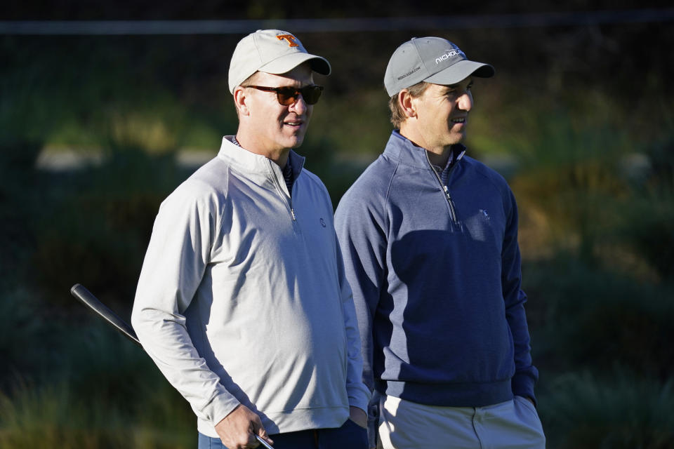 Peyton Manning, left, and his brother Eli Manning wait to hit from the first tee of the Spyglass Hill Golf Course during the first round of the AT&T Pebble Beach National Pro-Am golf tournament Thursday, Feb. 6, 2020, in Pebble Beach, Calif. (AP Photo/Tony Avelar)