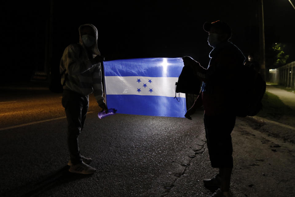 Members of a migrant caravan hold a Honduran national flag as they begin their journey in the hopes of reaching the United States, in San Pedro Sula, Honduras, Saturday, Jan. 15, 2022. (AP Photo/Delmer Martinez)