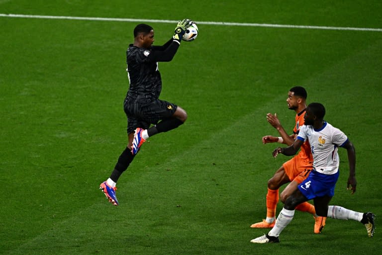 Le gardien de but français Mike Maignan s'empare du ballon devant l'attaquant néerlandais Cody Gakpo et le défenseur français Dayot Upamecano lors du match du Groupe D de l'Euro-2024 entre les Pays-Bas et la France, à Leipzig, le 21 juin 2024 (GABRIEL BOUYS)