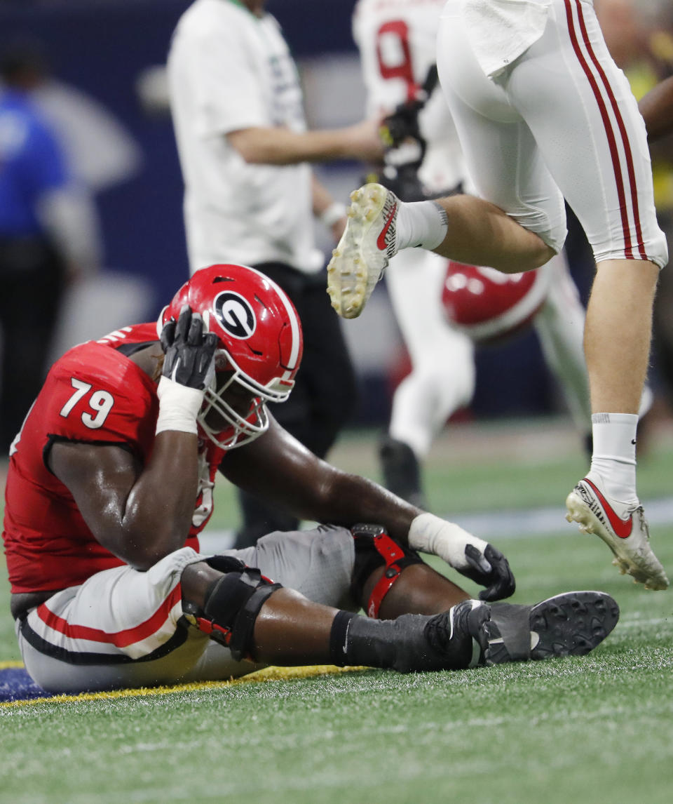 Georgia offensive lineman Isaiah Wilson (79) sits on the field as Alabama players celebrate after the Southeastern Conference championship NCAA college football game, Saturday, Dec. 1, 2018, in Atlanta. Alabama won 35-28. (AP Photo/John Bazemore)