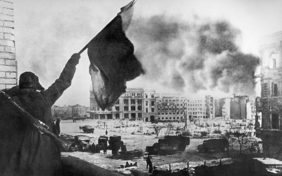 Soviet soldier waving the Red Banner over the central plaza of Stalingrad - TASS
