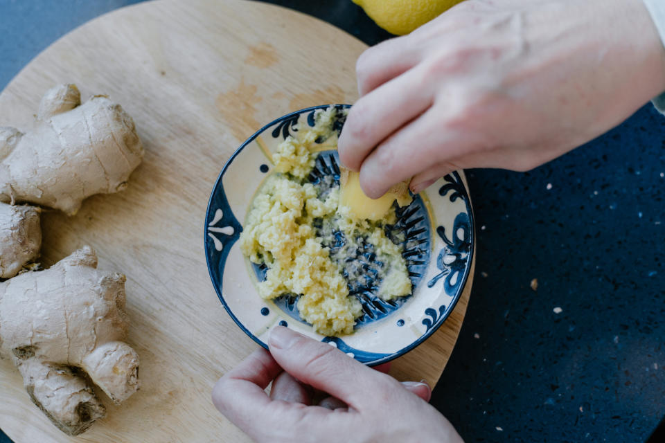 Woman grating ginger in a ceramic plate.