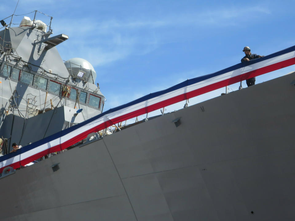 A shipbuilder at Bath Iron Works stands watches from atop the ship as the future USS Daniel Inouye is christened by the late Hawaiian senator's wife on Saturday, June 22, in Bath, Maine. Inouye, the ship's namesake, was a Medal of Honor recipient who broke racial barriers and represented Hawaii in the U.S. Senate for a half-century until his death in 2012. (AP Photo/David Sharp)