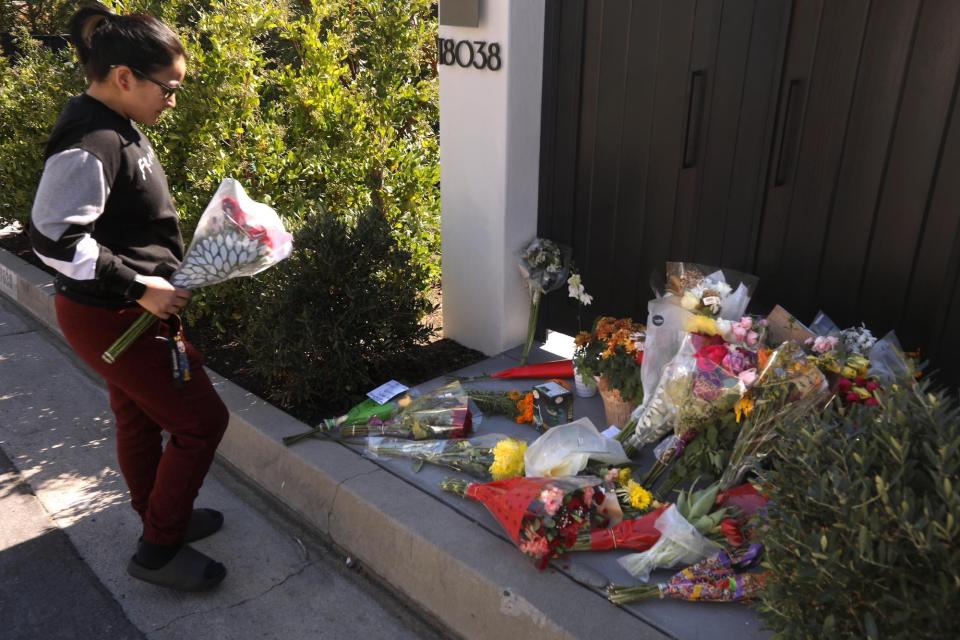 Daisy Muro, from Downey, prepares to leave flowers at a growing memorial for actor Matthew Perry in front of his home in Pacific Palisades on October 30, 2023.