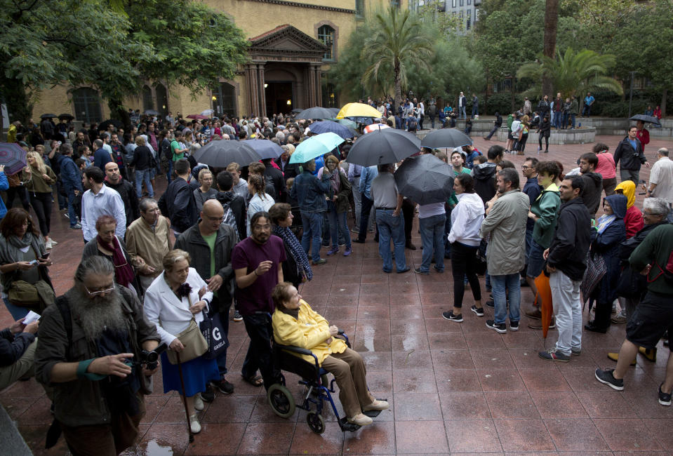 <p>Voters leave after casting their ballots as others wait in line at the Escola Industrial, a school assigned to be a polling station by the Catalan government in Barcelona. (AP) </p>