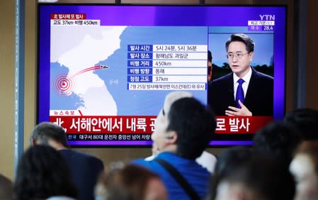 People watch a TV broadcasting a news report on North Korea firing two unidentified projectiles, in Seoul