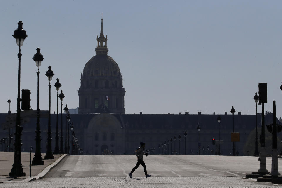 A man jogs in an empty Paris street, Wednesday, March 25, 2020. French President Emmanuel Macron urged employees to keep working in supermarkets, production sites and other businesses that need to keep running amid stringent restrictions of movement due to the rapid spreading of the new coronavirus in the country. The new coronavirus causes mild or moderate symptoms for most people, but for some, especially older adults and people with existing health problems, it can cause more severe illness or death. (AP Photo/Christophe Ena)