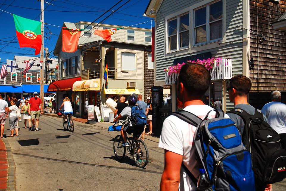 people biking and walking through a small street in Provincetown