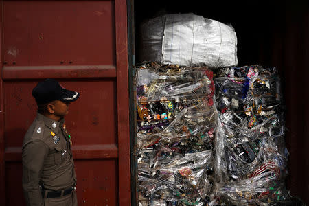 A policeman stands next to electronic waste hidden in a freight container during a search at Leam Chabang industrial estate, Chonburi province, Thailand, May 29, 2018. REUTERS/Athit Perawongmetha