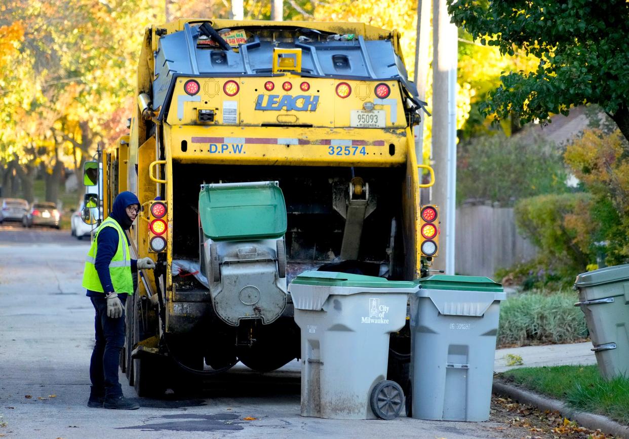 Amir Collins, a Milwaukee Department of Public Works city laborer, collects garbage on North 54th Street, north of West Garfield Avenue in Milwaukee on Monday, Oct. 30, 2023.