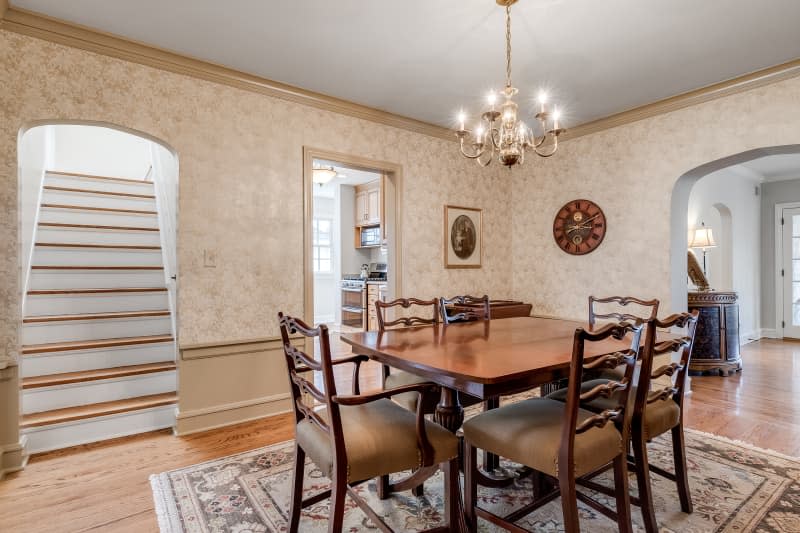 ELMHURST, IL, USA - MARCH 18, 2019: A large, old dining room with a wood table and a chandelier hanging above while looking towards other rooms.