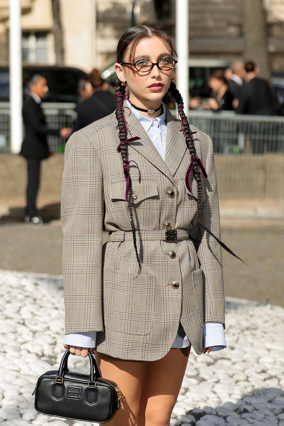 a woman with braids wearing a gray blazer and glasses