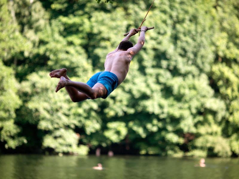 Ein Jugendlicher schwingt sich an der Krummen Lanke in Berlin ins Wasser. Foto: Kay Nietfeld