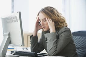 A young businesswoman is looking stressed as she works at her computer. Horizontal shot.