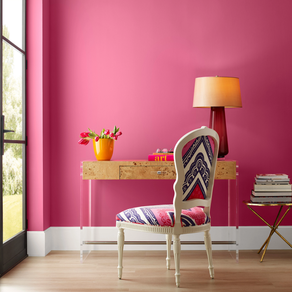 A room painted hot pink with a desk and chair against the wall