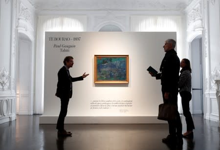 People stand next to Paul Gauguin's "Te Bourao II" (The Purao Tree) painting (1897) at Artcurial's auction house in Paris