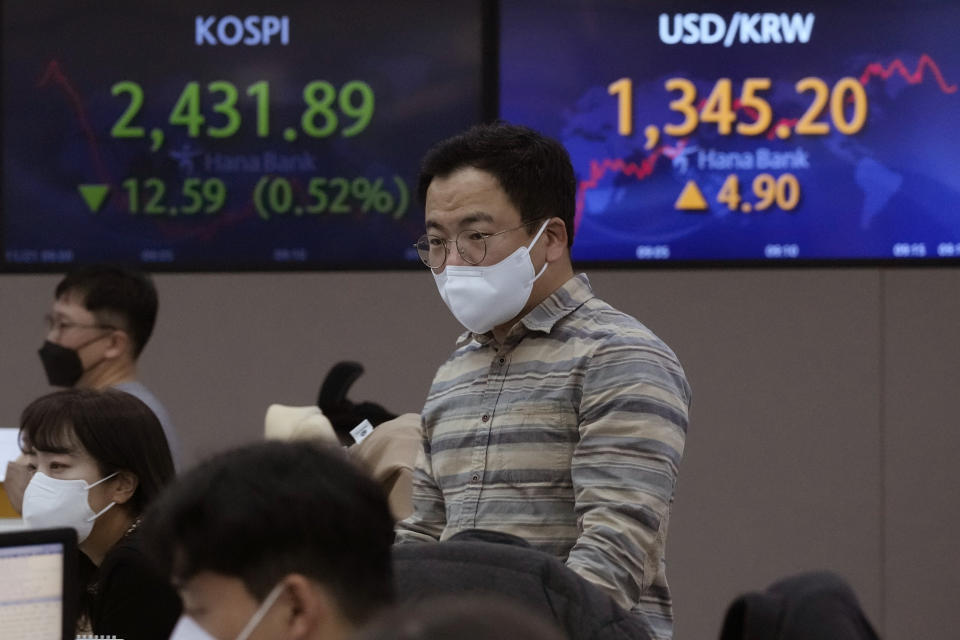 A currency trader watches monitors near screens showing the Korea Composite Stock Price Index (KOSPI), left, and the exchange rate of South Korean won against the U.S. dollar, at the foreign exchange dealing room of the KEB Hana Bank headquarters in Seoul, South Korea, Monday, Nov. 21, 2022. Asian stock markets sank Monday after Wall Street ended with a loss for the week amid anxiety about Federal Reserve plans for more interest rate hikes to cool inflation. (AP Photo/Ahn Young-joon)