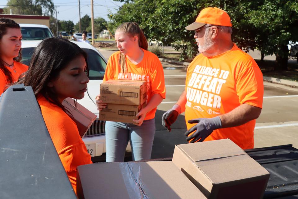 Ariele Runquillo, Kaci Willburn from Holy Cross Catholic Academy and Dave Kruonick load boxes food, personal items and books in the back of a truck during the The Alliance to Defeat Hunger at Catholic Charities of the Texas Panhandle on Thursday morning.