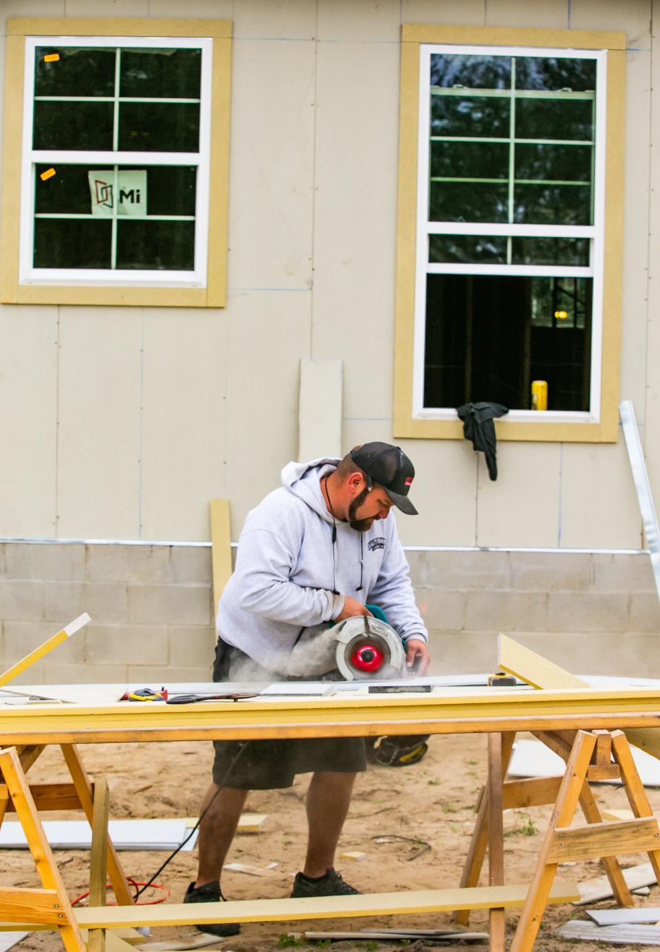 Construction worker Steven Nilsen with Quality Framing cuts siding for a new home being built in Woodfield Crossings late last year.