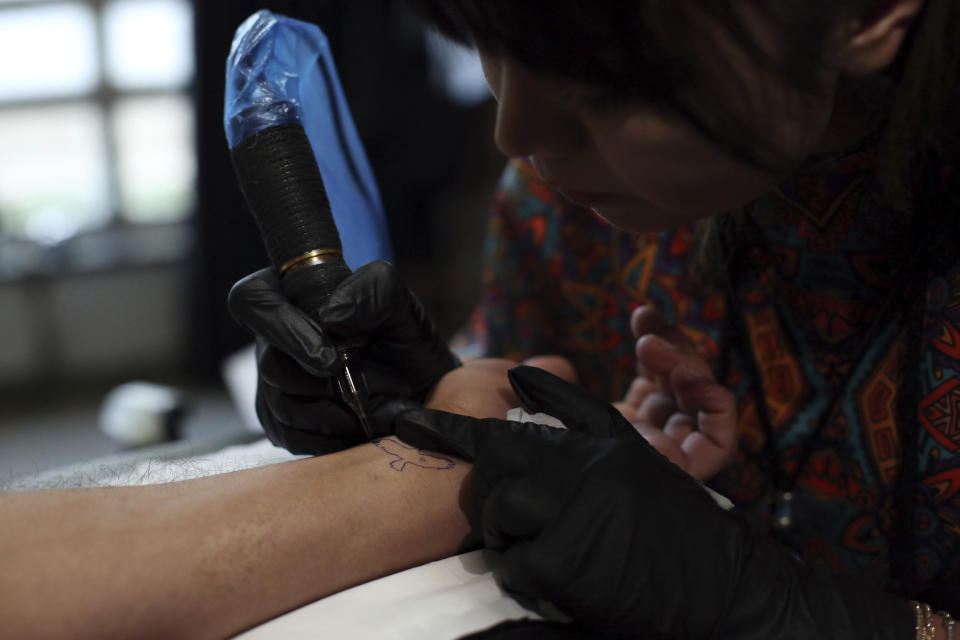 In this Saturday, 9, 2019, photo, Suraya Shaheedi, 26, Tattoo artist, right, pierced tattoo to a male customer in Kabul, Afghanistan. It’s been 18 months since Shaheedi started her mobile tattoo shop in the capital, Kabul. She’s received death threats for taking on the taboo of the ink-on-skin drawings she does — as well as being a single woman willing to work with men.(AP Photo/Rahmat Gul)