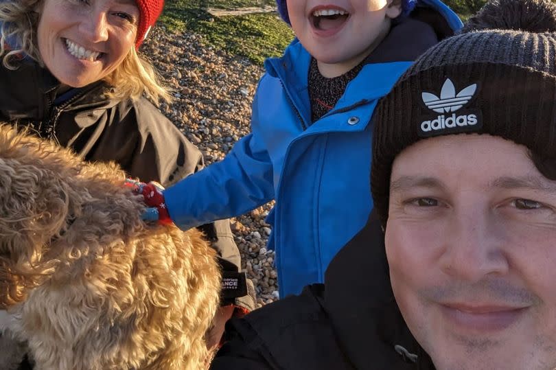 A family of three and their dog at a beach