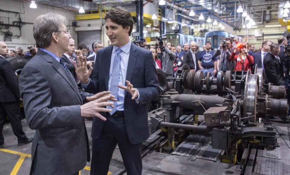 Prime Minister Justin Trudeau listens to director of maintenance Carl Arsenaeault as he tours a garage of the Montreal Transportation Commission, Wednesday, April 6, 2016 in Montreal. THE CANADIAN PRESS/Paul Chiasson