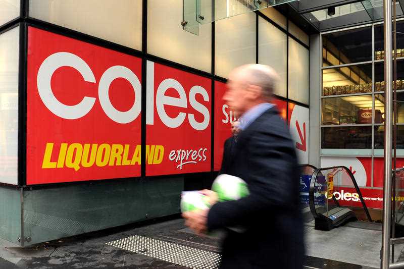 A man walks past a Coles supermarket.