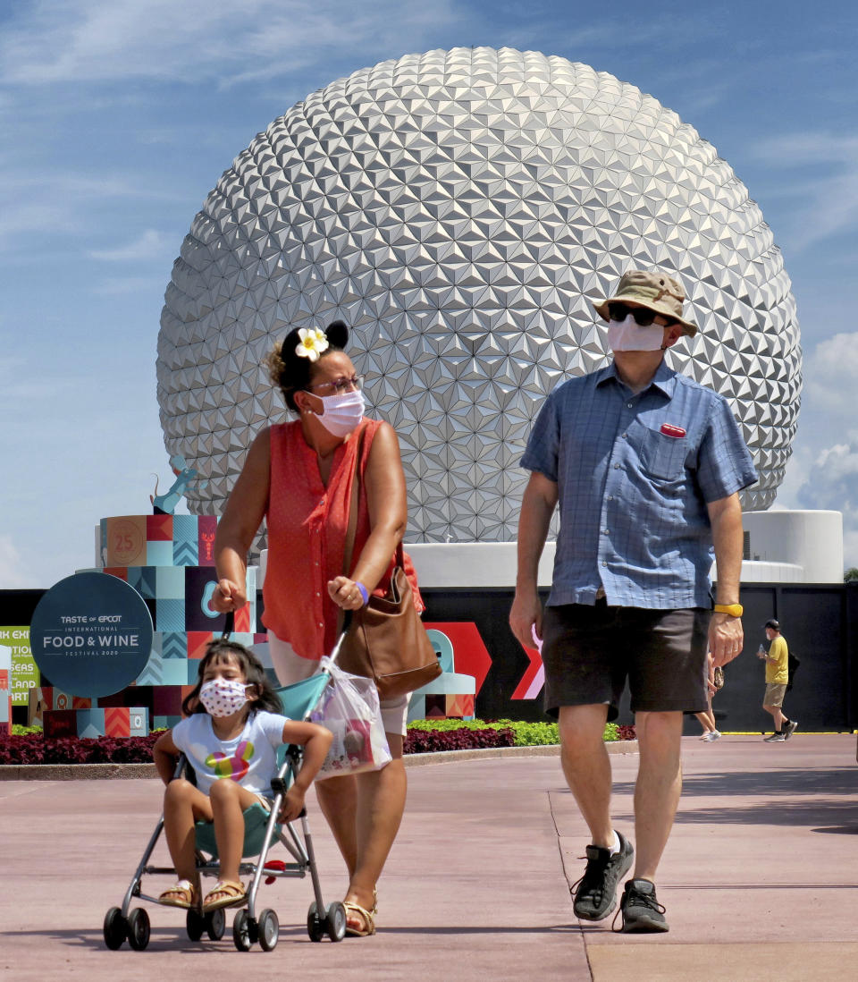 Guests arrive to attend the official re-opening day of Epcot at Walt Disney World in Lake Buena Vista, Fla., Wednesday, July 15, 2020. All four of Disney's Florida parks are now open, including Hollywood Studios, the Magic Kingdom and Animal Kingdom, with limited capacity and safety protocols in place in response to the coronavirus pandemic. (Joe Burbank/Orlando Sentinel via AP)