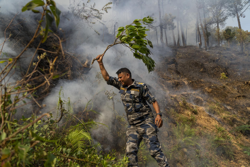 A policeman douses a forest fire in Shivapuri National Park on the outskirts of of in Lalitpur, Nepal, Tuesday, April 30, 2024. (AP Photo/Niranjan Shrestha)