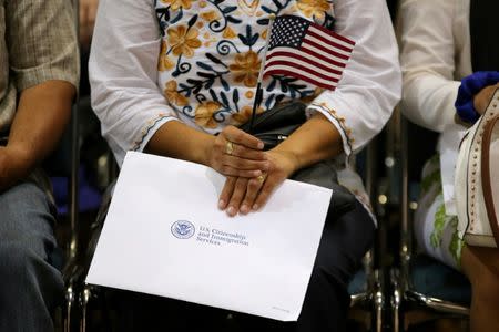 FILE PHOTO: An attendee holds her new country's flag and her naturalization papers as she is sworn in during a U.S. citizenship ceremony in Los Angeles, U.S., July 18, 2017. REUTERS/Mike Blake/File Photo