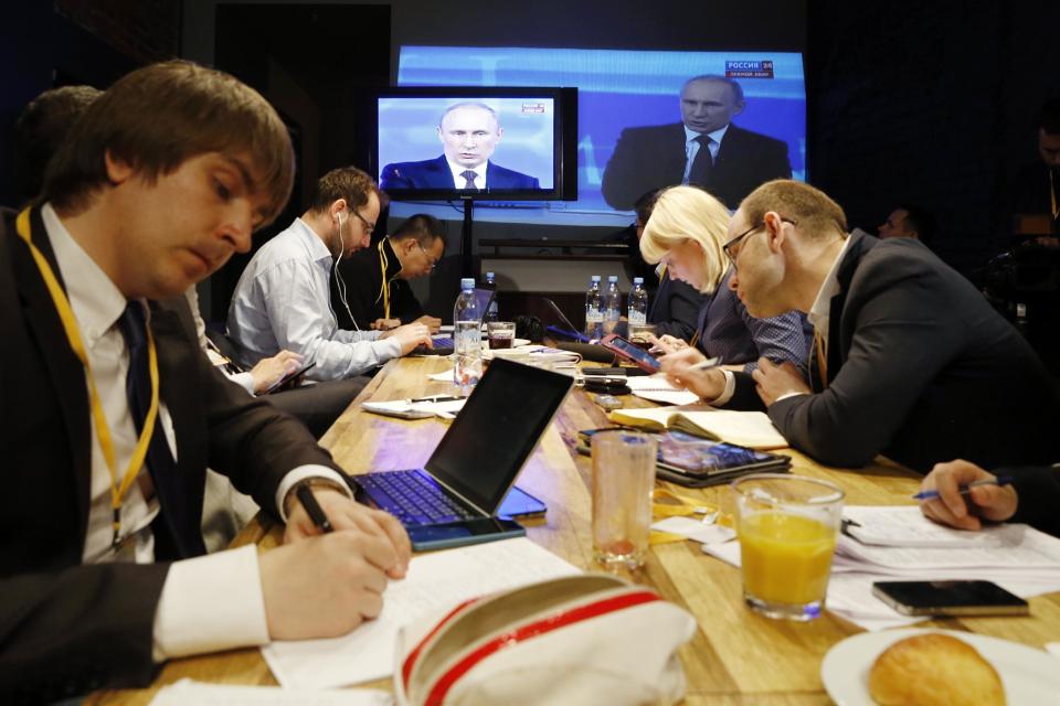 Reporters listen to Russian President Vladimir Putin's speech, displayed on TV screens during a nationally televised question-and-answer session in Moscow, Thursday, April 17, 2014. (AP Photo/Pavel Golovkin)