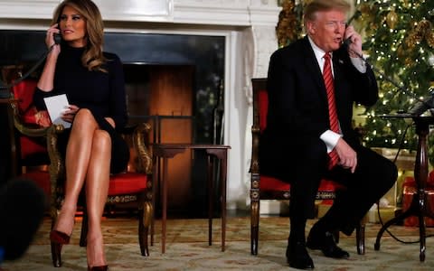 President Donald Trump and first lady Melania Trump speak on the phone while sharing updates to track Santa's movements from the NORAD Santa Tracker on Christmas Eve - Credit:  Jacquelyn Martin/AP