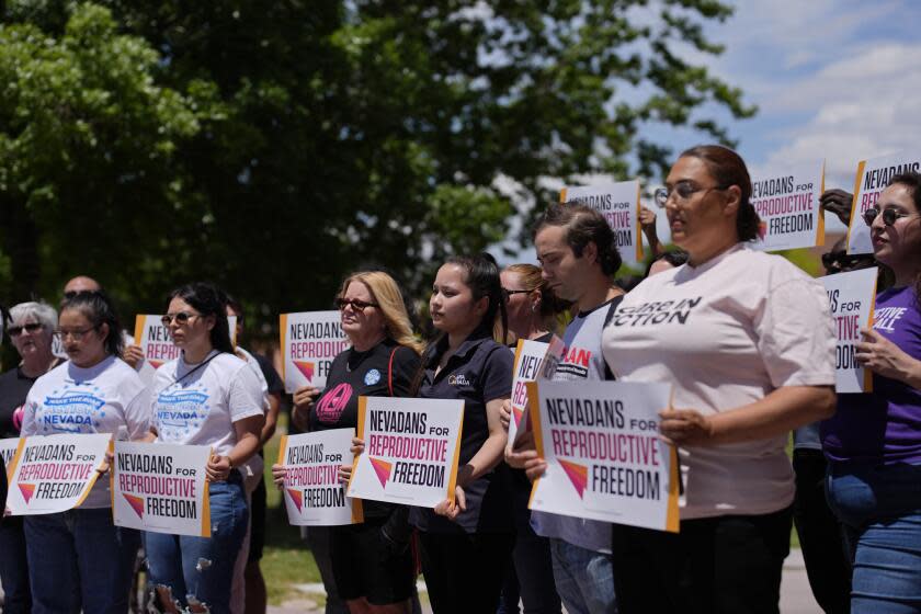 People hold signs during a news conference by Nevadans for Reproductive Freedom, Monday, May 20, 2024, in Las Vegas. Abortion access advocates in Nevada said Monday they've submitted twice the number of petition signatures needed to qualify for a ballot measure aimed at enshrining what they term reproductive rights in the state constitution. (AP Photo/John Locher)