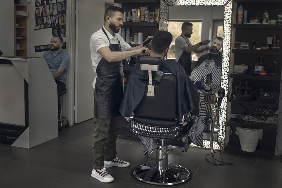 Hairdresser Hasan Derek, 36, from Syria, cuts the hair of a customer who was originally from Kurdistan, in his hair salon in Akalla, Rinkeby-Kista borough, Stockholm, Sweden, Tuesday, April 28, 2020. The coronavirus has taken a disproportionate toll among Sweden's immigrants. Many in these communities are more likely to live in crowded households and are unable to work remotely. There also are concerns the message has not reached everyone in immigrant neighborhoods. (AP Photo/Andres Kudacki)