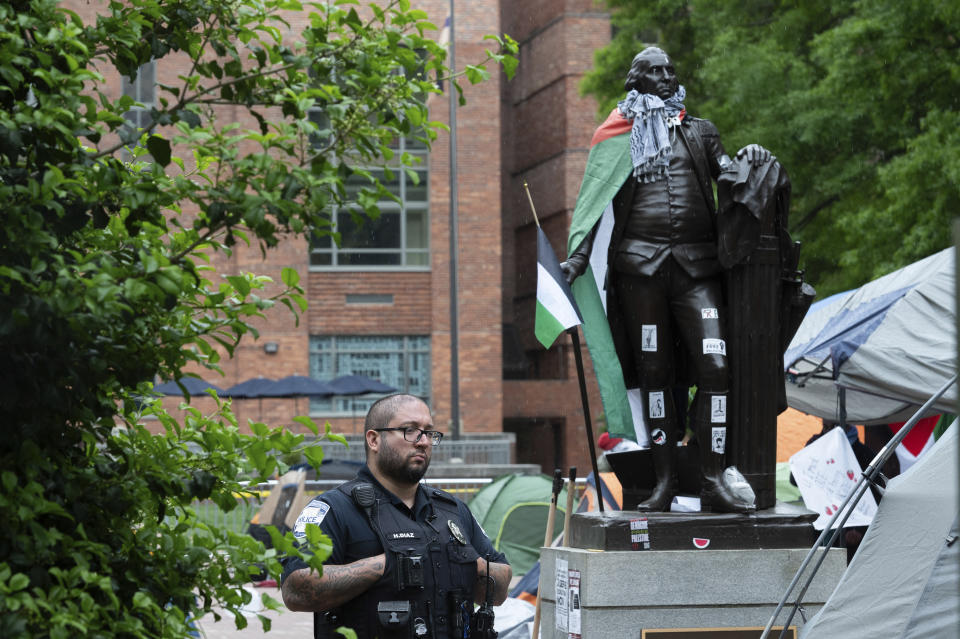 A George Washington University police officer stands near the statue of George Washington in the University Yard as student protest the Israel-Hamas war, at George Washington University in Washington, Saturday, April 27, 2024. (AP Photo/Cliff Owen)