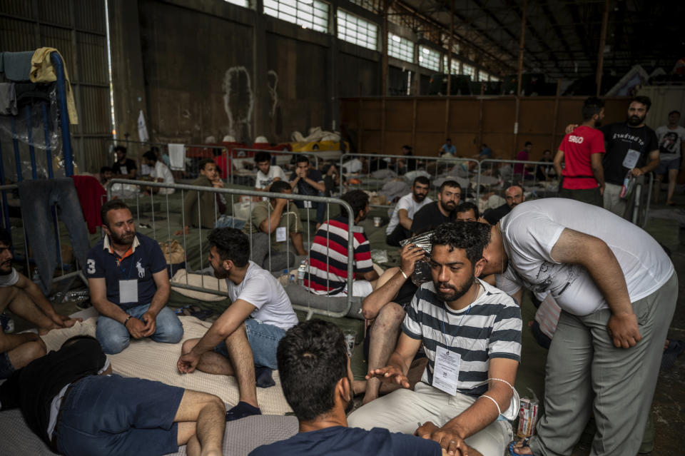 Survivors of a shipwreck sit inside a warehouse where are taking shelter at the port in Kalamata town, about 240 kilometers (150miles) southwest of Athens, on Thursday, June 15, 2023. A fishing boat crammed to the gunwales with migrants trying to reach Europe capsized and sank Wednesday June 14 off the coast of Greece, authorities said, leaving at least 79 dead and many more missing in one of the worst disasters of its kind this year. (Angelos Tzortzinis, Pool via AP)